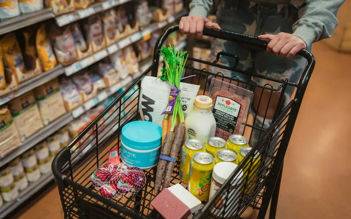 Shopper pushing a cart full of groceries down a store aisle