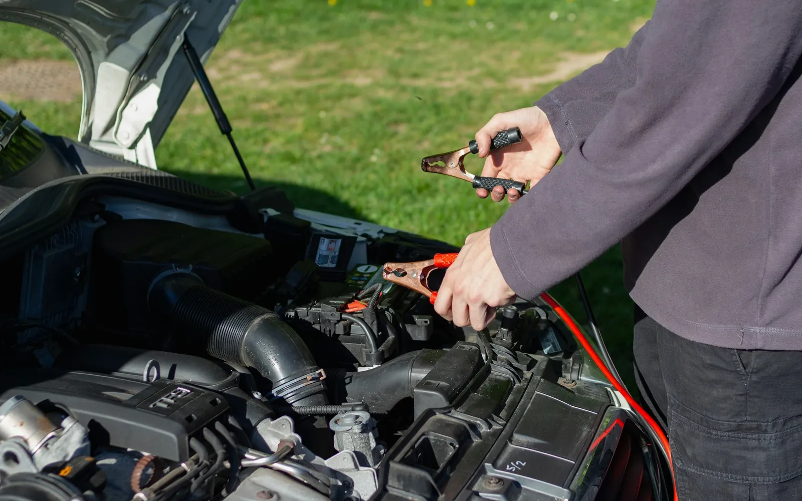 Jumper cables connected to a car battery under the hood