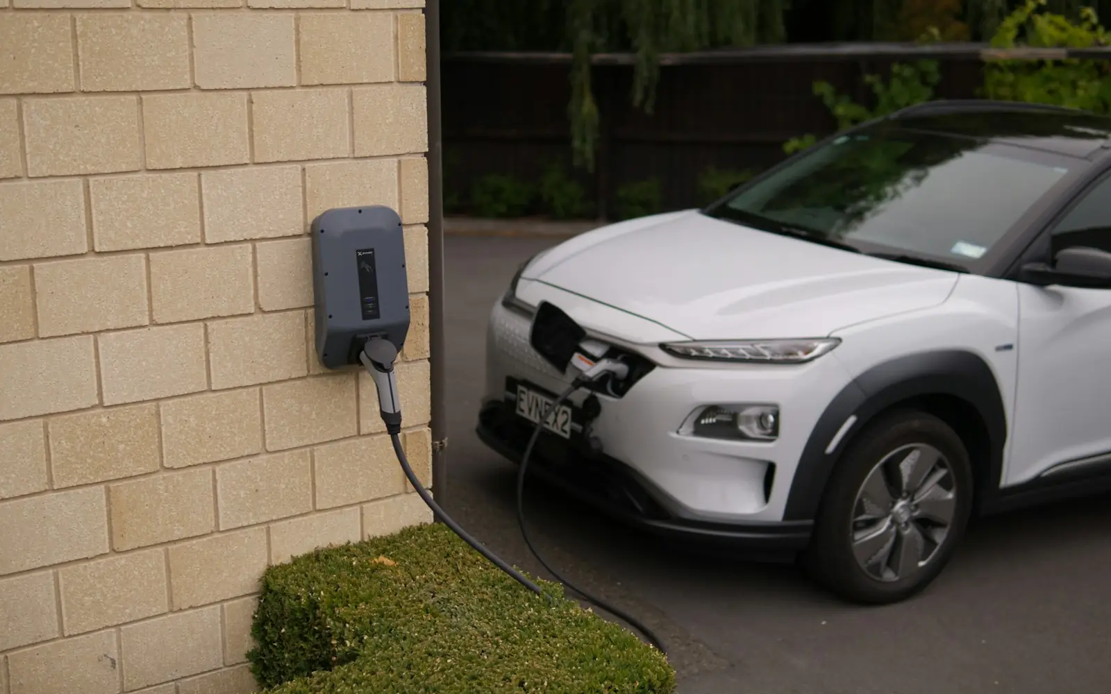 White electric SUV plugged into a wall-mounted home charger